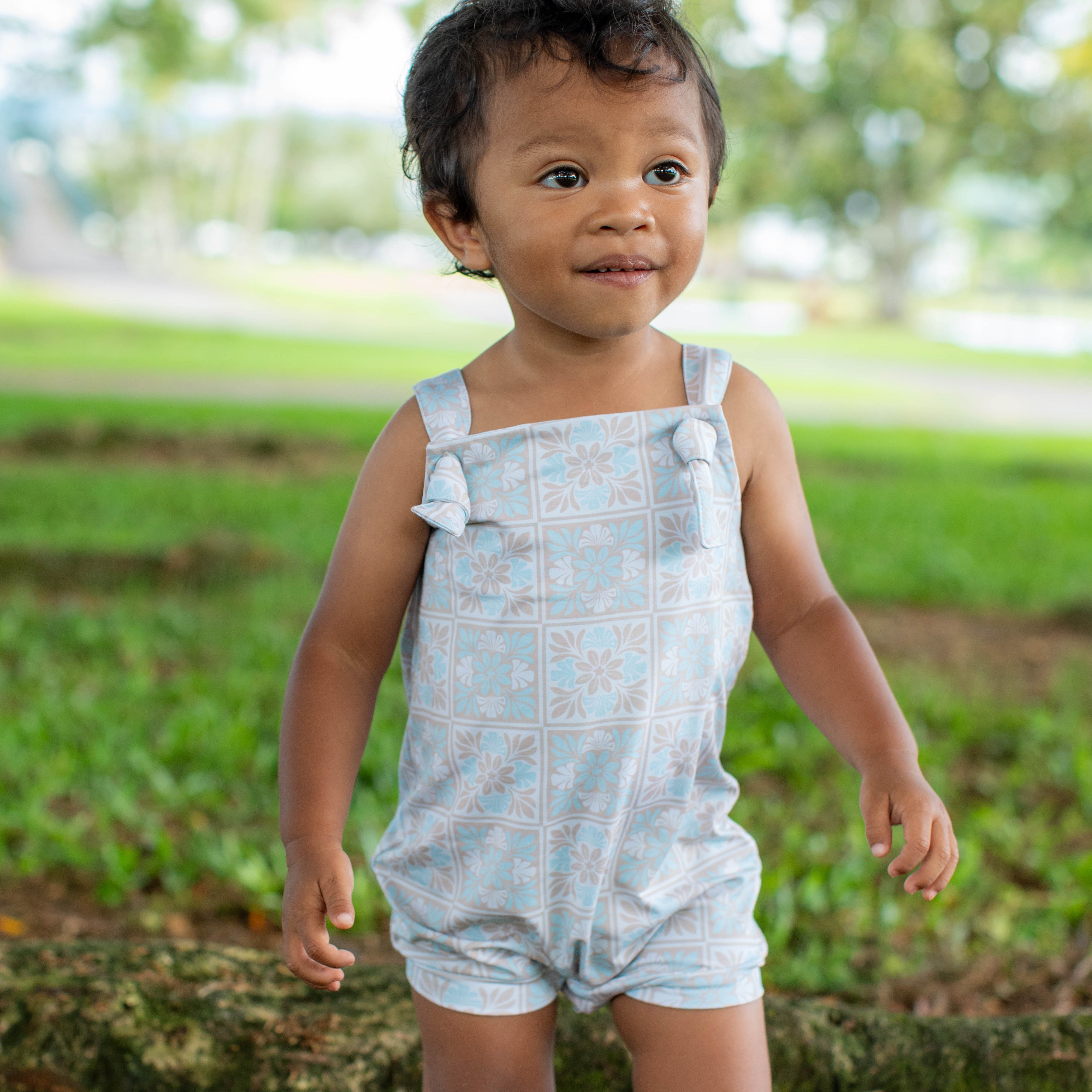 Child wearing a light blue overall in a park setting