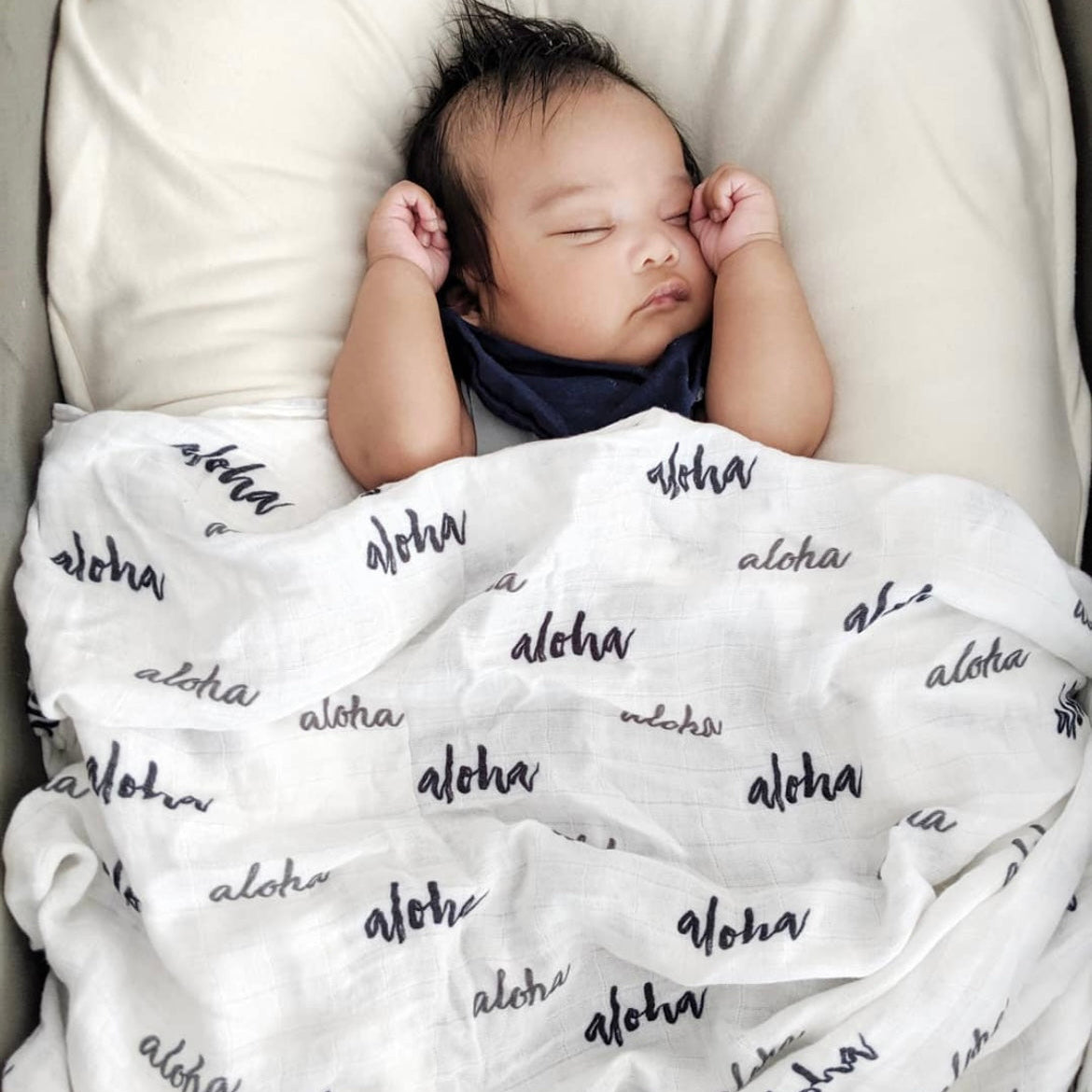 Newborn baby sleeping under a blanket with 'aloha' text