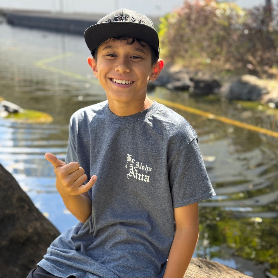 Child giving a shaka by a pond
