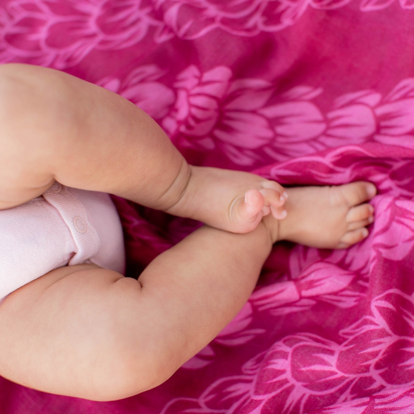 Baby legs and feet on a pink pakalana lei blanket