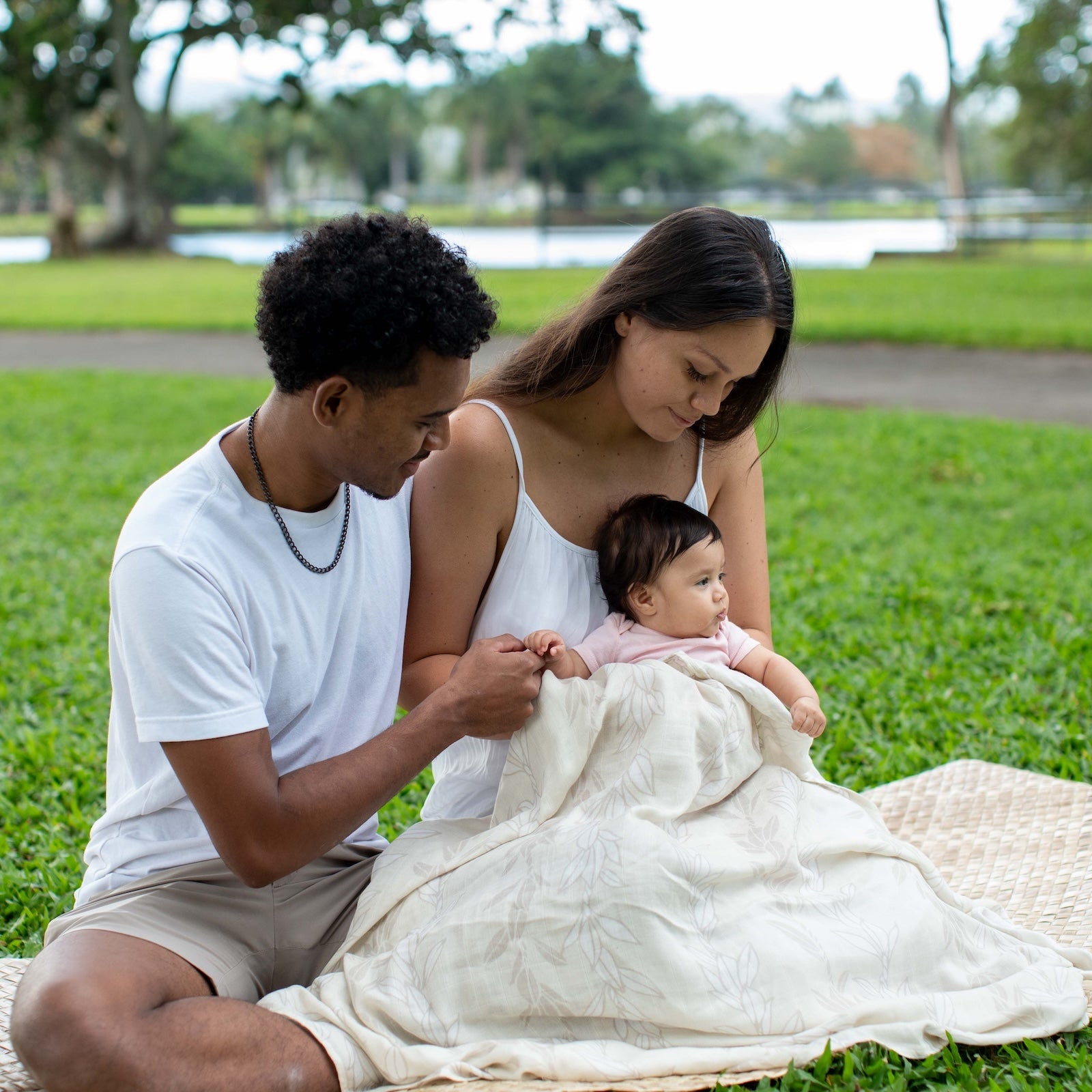 Family of three sitting on a blanket in a park