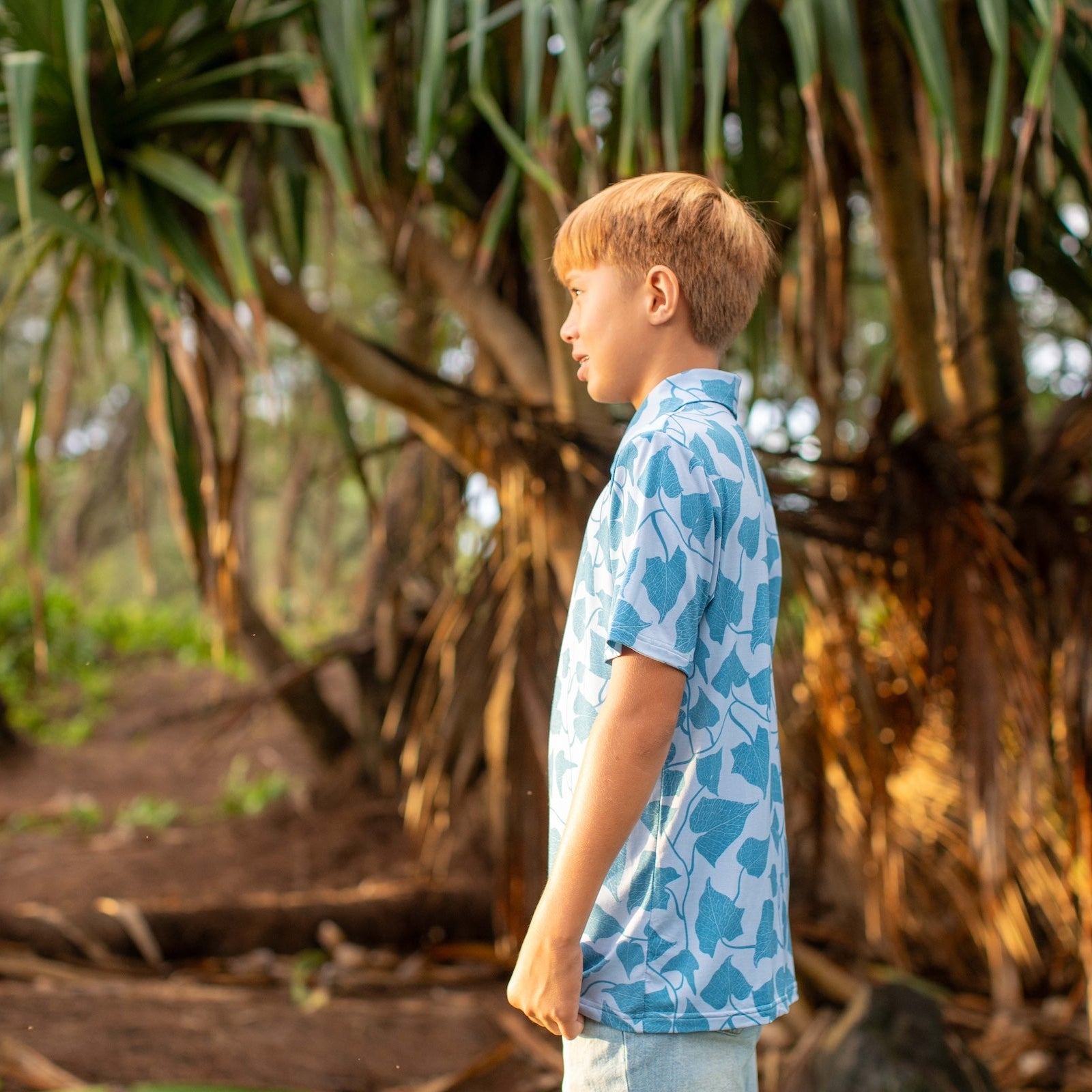 Young boy standing in a forest with hala trees