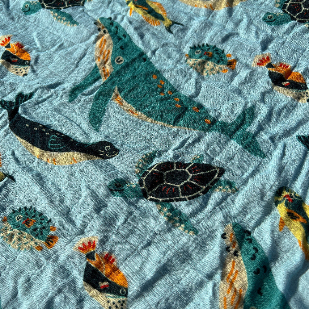 Fabric with sea-themed pattern featuring turtles, fish, and seals on a light blue background.